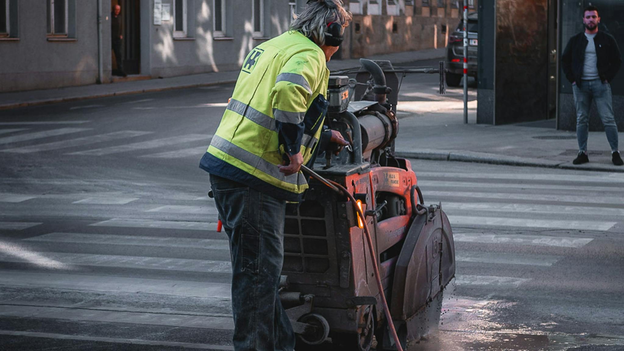 Construction worker using machinery on a street in Vienna, Austria during the day.