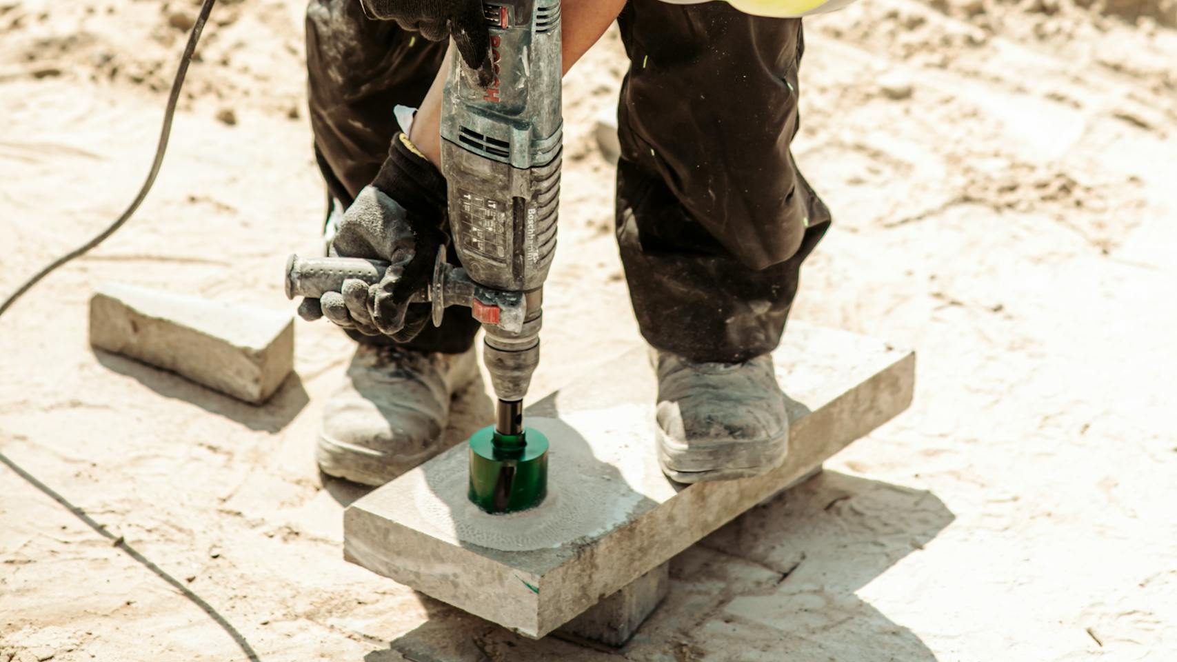 Worker operates a drill on a construction site in Grójec, Poland, showcasing industry.